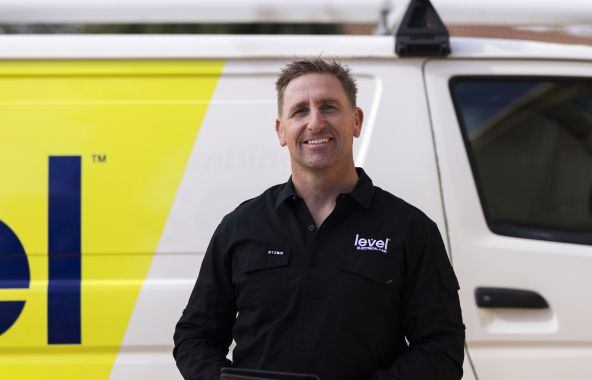 level electrical + air hvac technician smiling and standing in front of work van