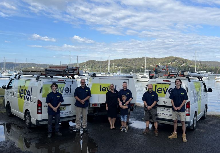 Calvin and Kristy Hudson with the Level Electrical & Air West Gosford team and branded service vehicles on the Central Coast.