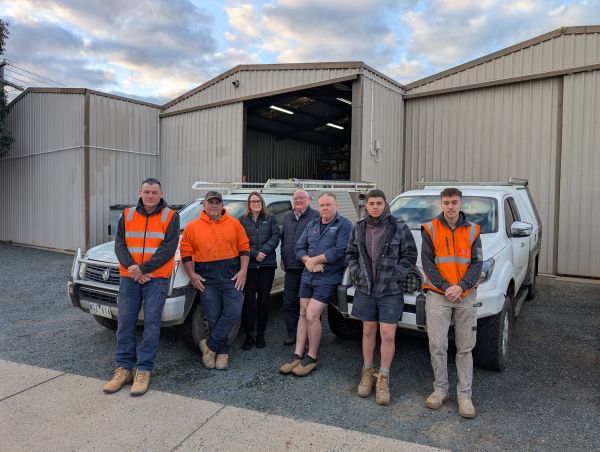 Richard Grogan and the Level Plumbing Shepparton team standing in front of their vehicles at the Shepparton workshop.