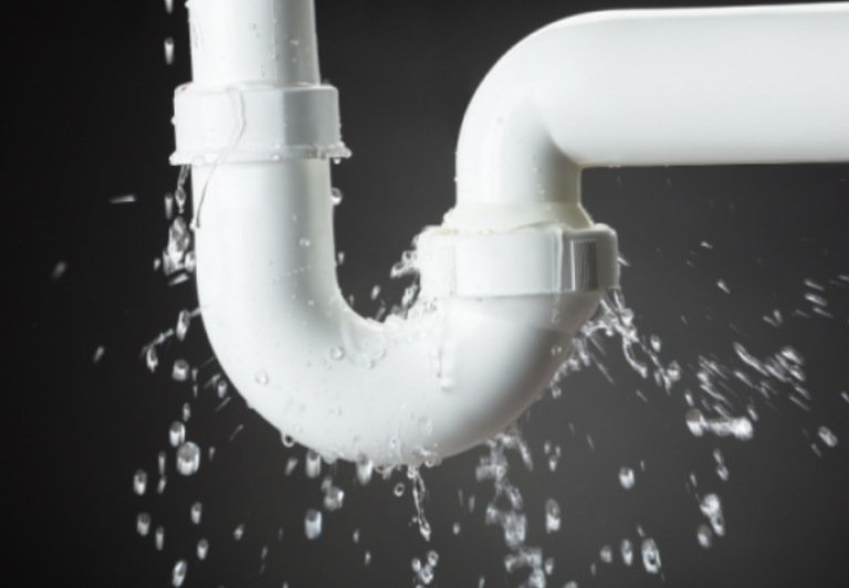 a white under-sink pipe leaking water