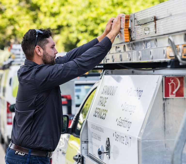 Male Plumber in Adelaide removing his ladder from the roof of his work vehicle, getting ready to complete high quality plumbing repairs