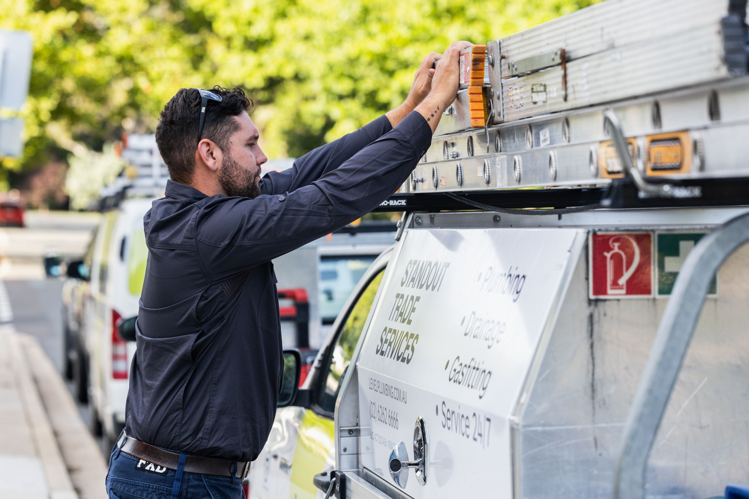 Male Plumber in Adelaide removing his ladder from the roof of his work vehicle, getting ready to complete high quality plumbing repairs