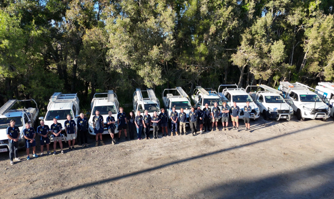 The Bones Plumbing team standing in front of their branded vehicles on the Sunshine Coast.