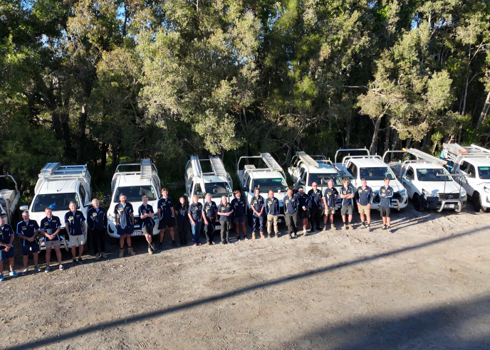 The Bones Plumbing team standing in front of their branded vehicles on the Sunshine Coast.