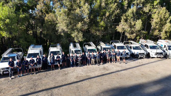 The Bones Plumbing team standing in front of their branded vehicles on the Sunshine Coast.
