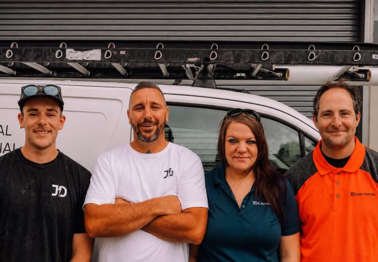 Four members of the Level Electrical Lake Macquarie team standing in front of their electrical service vehicle.