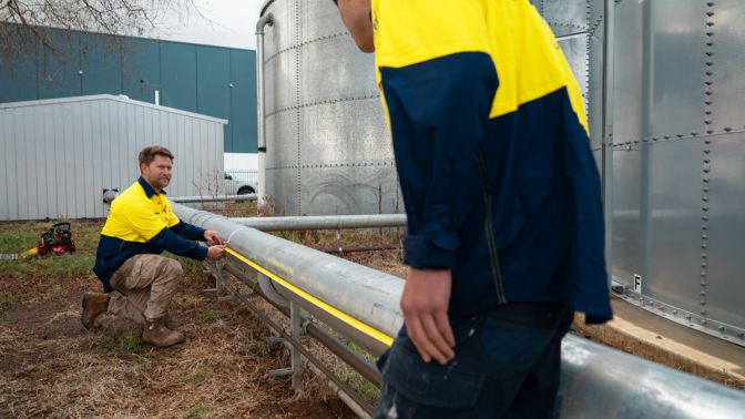 Level plumbers repairing above ground pipe during burst pipe repair work in Australia