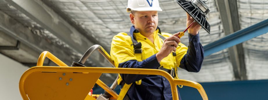 Level electrical technician installing commercial lighting equipment on site in Australia