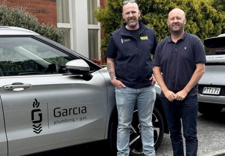 Business owners from Garcia Plumbing & Gas standing beside branded vehicle, demonstrating independent branding within the Level alliance