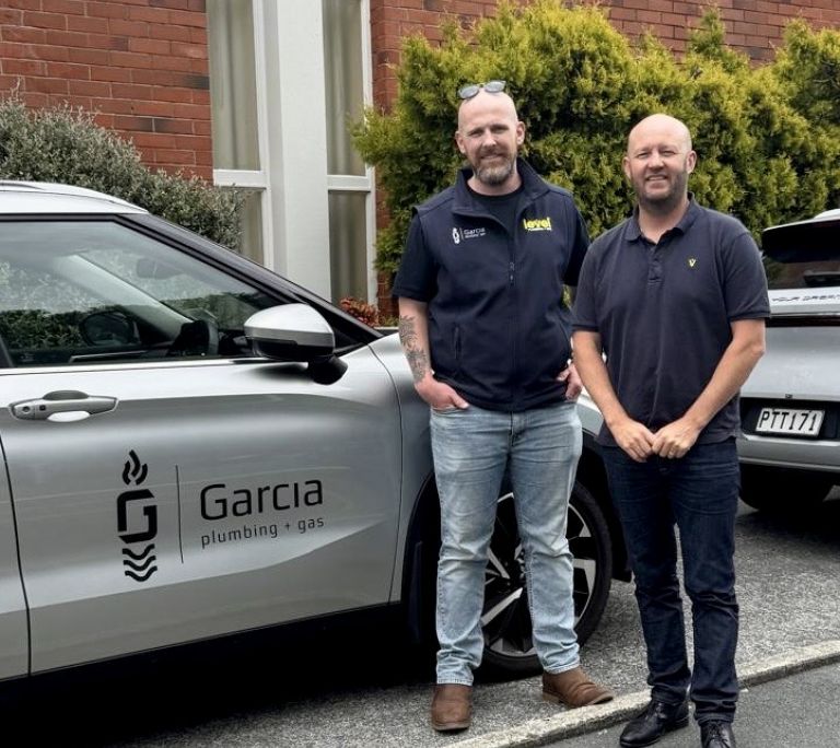 Business owners from Garcia Plumbing & Gas standing beside branded vehicle, demonstrating independent branding within the Level alliance