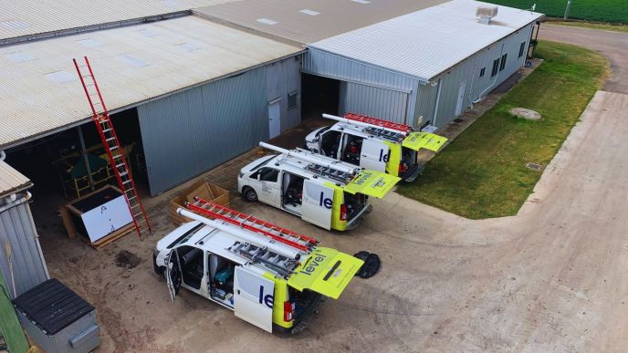 Level Electrical service vehicles parked at a commercial warehouse site in Australia during electrical works