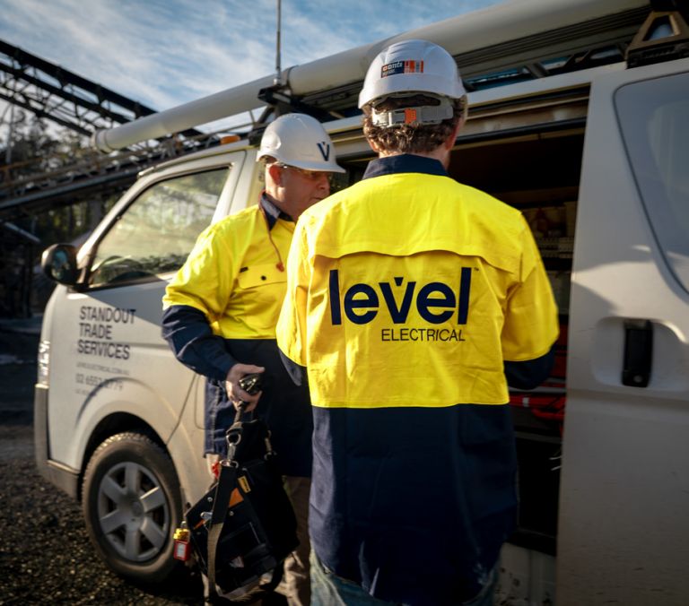 Level electrical technicians preparing tools beside a service vehicle on a commercial site in Australia
