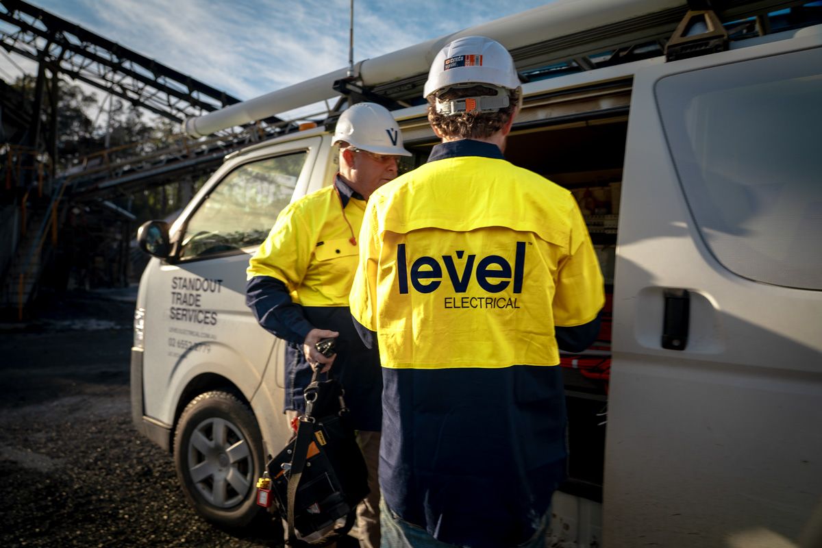 Level electrical technicians preparing tools beside a service vehicle on a commercial site in Australia