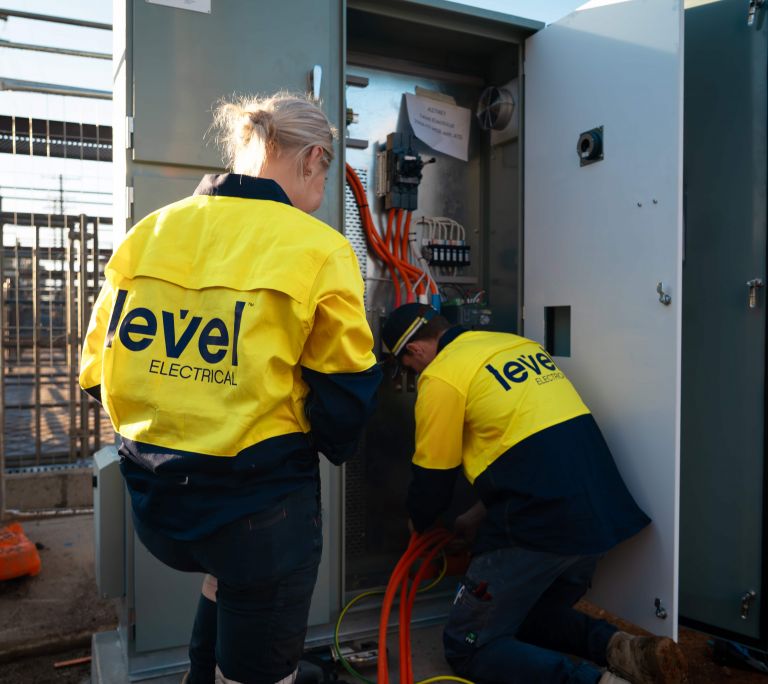 Level Electrical technicians installing and wiring a switchboard on a commercial electrical site in Australia