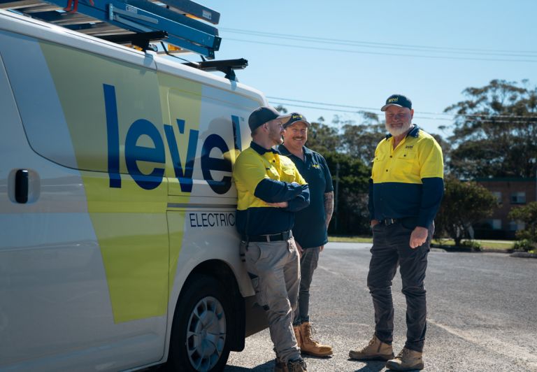 Level Electrical team members standing beside a branded service van on site in Australia