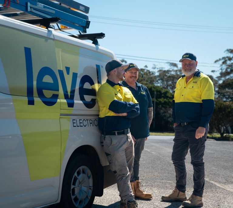 Level Electrical team members standing beside a branded service van on site in Australia