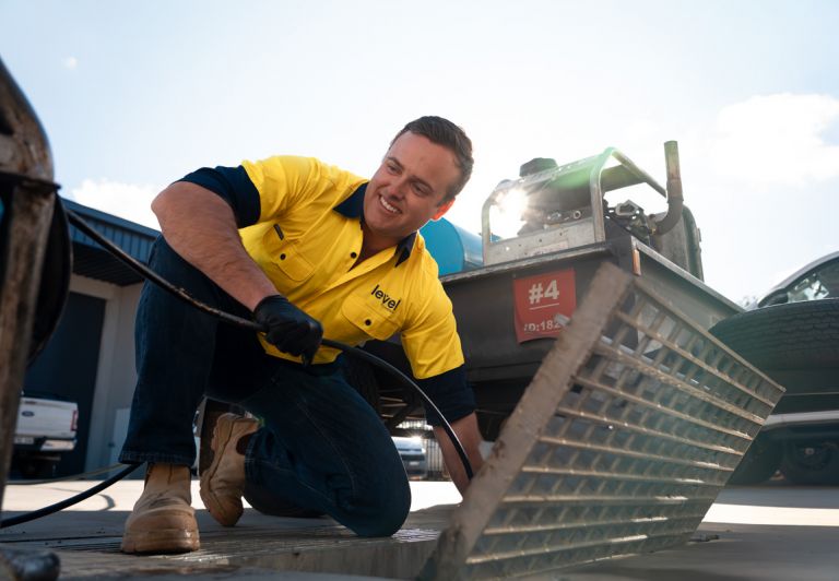 Level plumber clearing a blocked drain during plumbing maintenance work in Australia