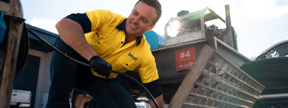Level plumber clearing a blocked drain during plumbing maintenance work in Australia