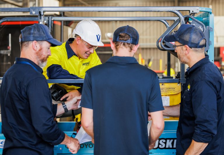 Level plumbing and electrical technicians working together on equipment at a commercial job site in Australia
