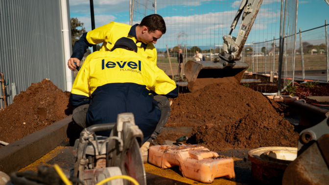 Level plumbing technicians installing underground infrastructure services on a construction site in Australia