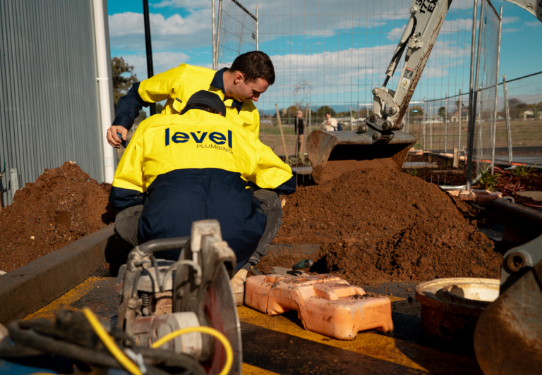 Level plumbing technicians installing underground infrastructure services on a construction site in Australia