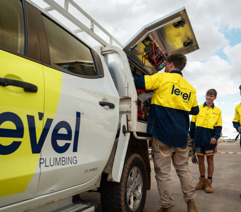 Level plumbing technicians accessing equipment from a service truck on site in Australia