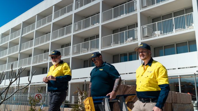 Level plumbing and electrical technicians walking onto a commercial construction project site in Australia