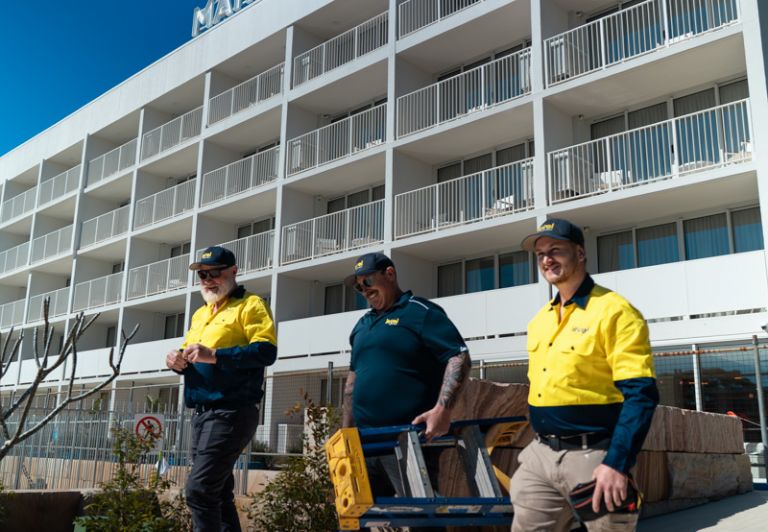 Level plumbing and electrical technicians walking onto a commercial construction project site in Australia