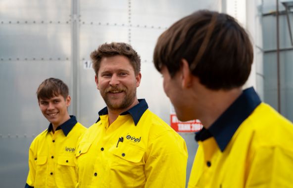 Level plumbing and electrical technicians speaking together on a job site in Australia