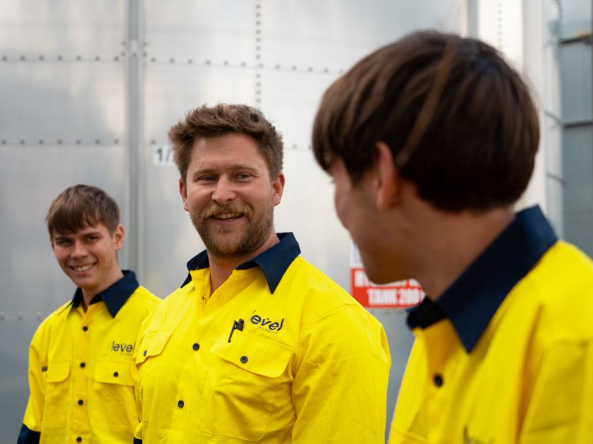 Level plumbing and electrical technicians speaking together on a job site in Australia