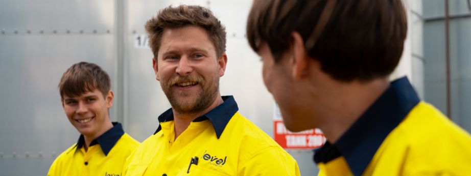 Level plumbing and electrical technicians speaking together on a job site in Australia