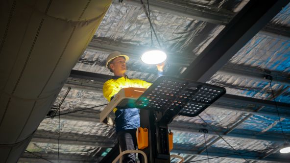Level electrician installing lighting in commercial space