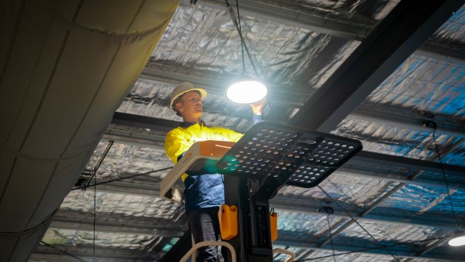 Level electrician installing lighting in commercial space
