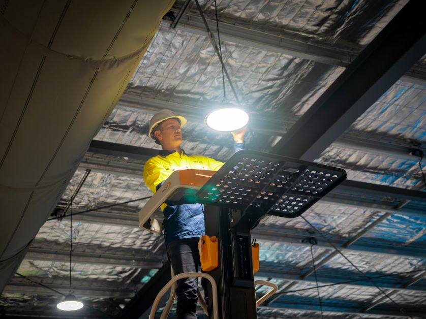 Level electrician installing lighting in commercial space