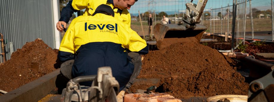 Level plumbers repairing underground pipe during leak detection and excavation work