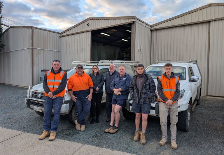 Richard Grogan and the Level Plumbing Shepparton team standing in front of their vehicles at the Shepparton workshop.