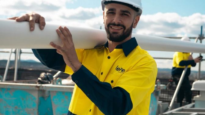 Level Plumbing Canberra technician carrying pipework on a commercial project site in the ACT, representing professional plumbing services across Australia.