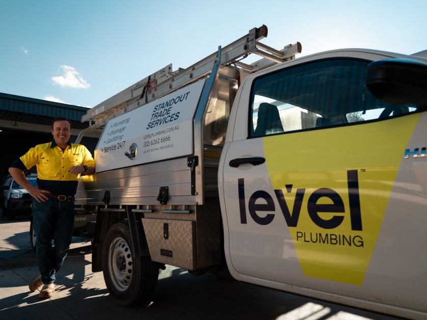 Level Plumbing Canberra technician standing beside fully equipped emergency response vehicle ready to assist customers