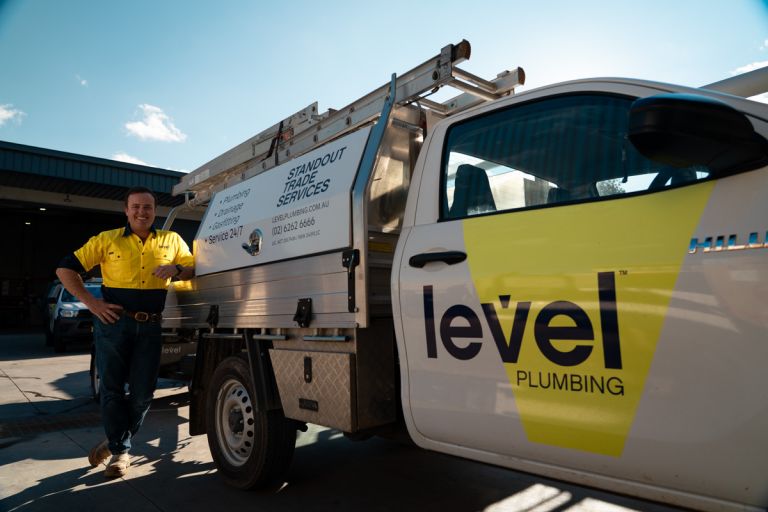 Level Plumbing Canberra technician standing beside fully equipped emergency response vehicle ready to assist customers