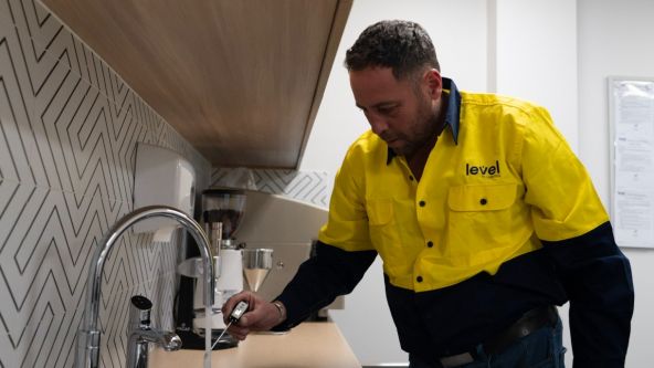 Level Plumbing Canberra technician testing water temperature at a commercial sink to ensure hot water system performance and safety