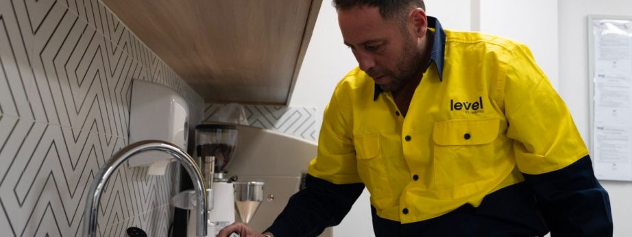 Level Plumbing Canberra technician testing water temperature at a commercial sink to ensure hot water system performance and safety