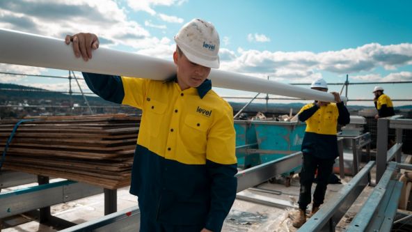 Level Plumbing Canberra technicians carrying roofing materials on a commercial rooftop during installation works in the ACT