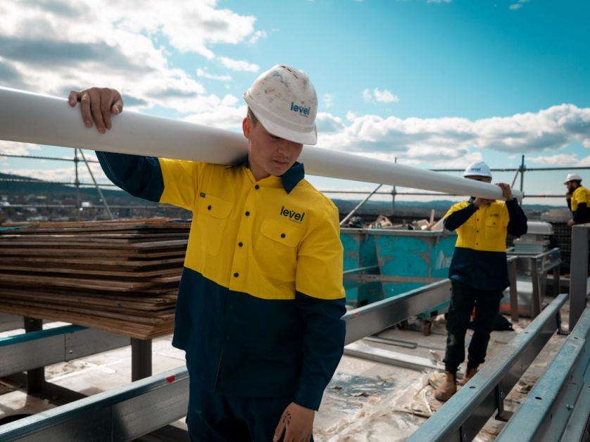 Level Plumbing Canberra technicians carrying roofing materials on a commercial rooftop during installation works in the ACT
