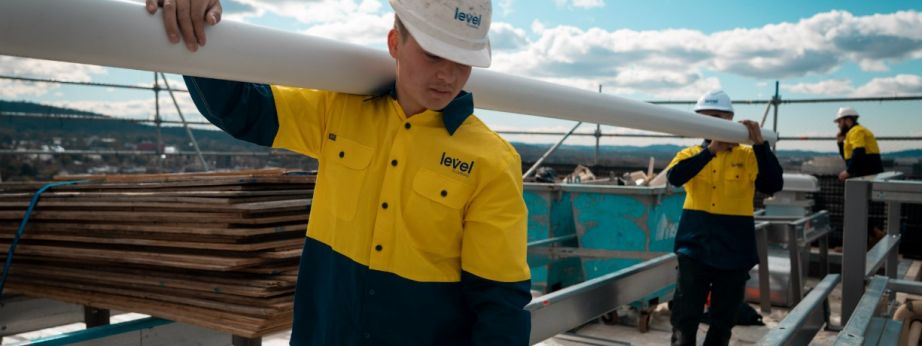 Level Plumbing Canberra technicians carrying roofing materials on a commercial rooftop during installation works in the ACT